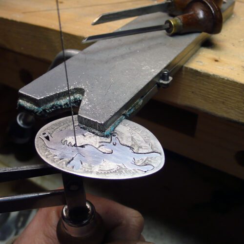 Handcrafted and recycled sterling silver leaping fox and dancing vixen necklace being cut out of the silver coin