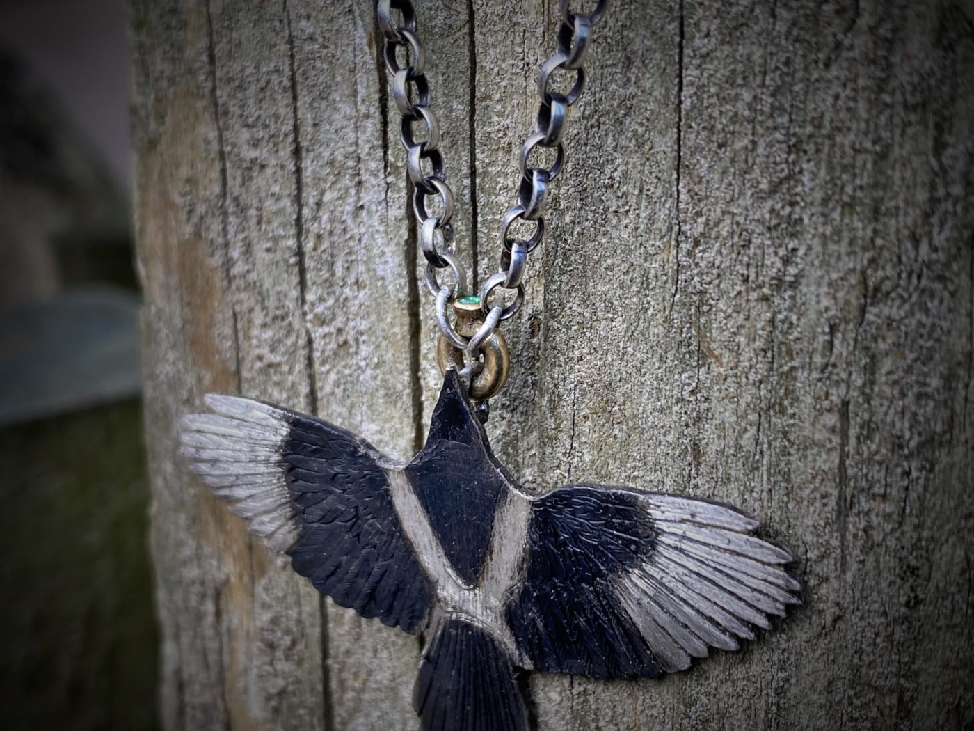 handmade silver Magpie necklace flying off with 18ct gold and emerald treasure in beak. Made in England with love and passion for treasure. Each piece is completely unique and original made in artisan studio in Cambridge and Newcastle