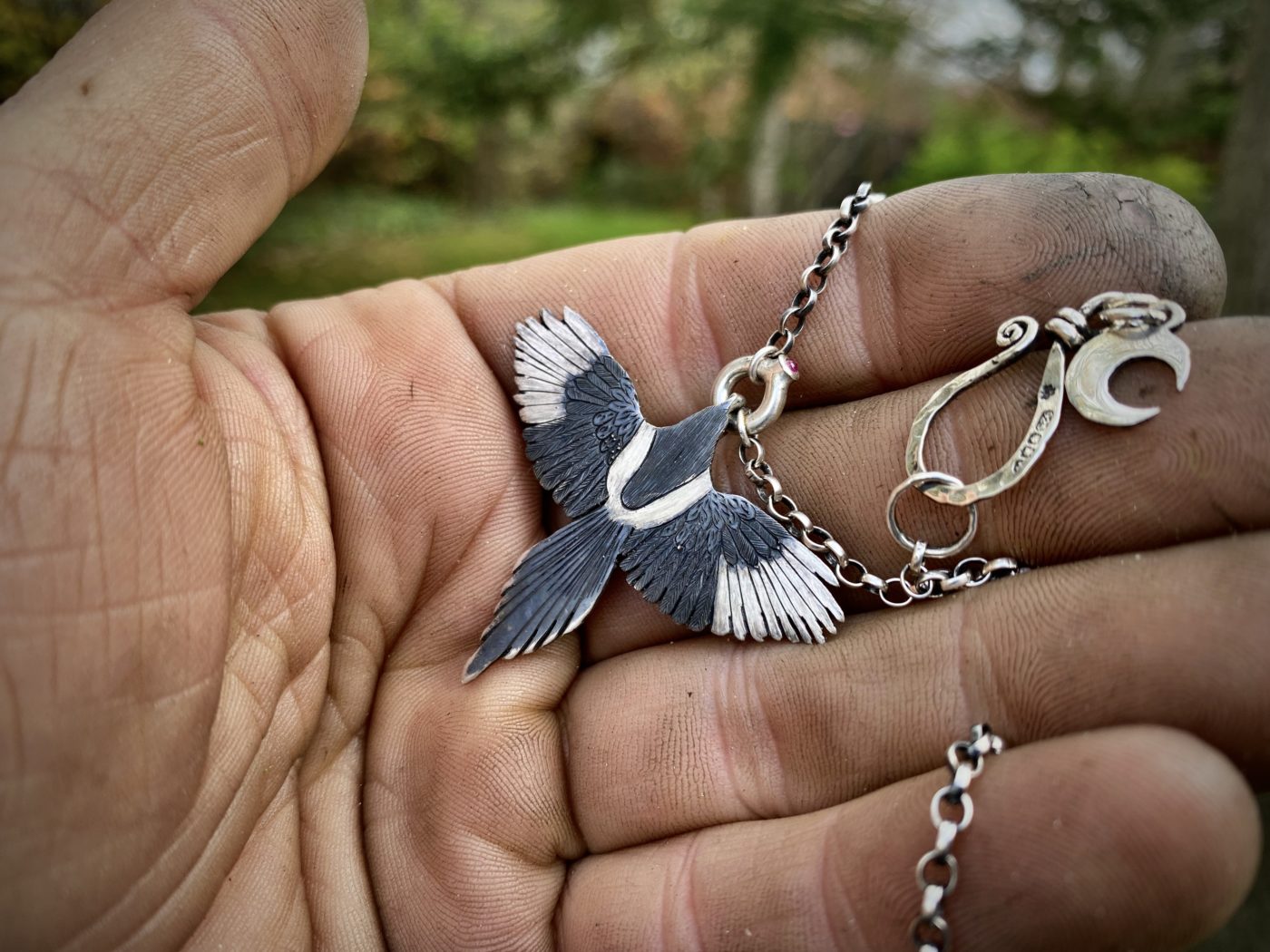 handmade silver Magpie necklace flying off with silver treasure in beak. Made in England with love and passion for treasure. Each piece is completely unique and original