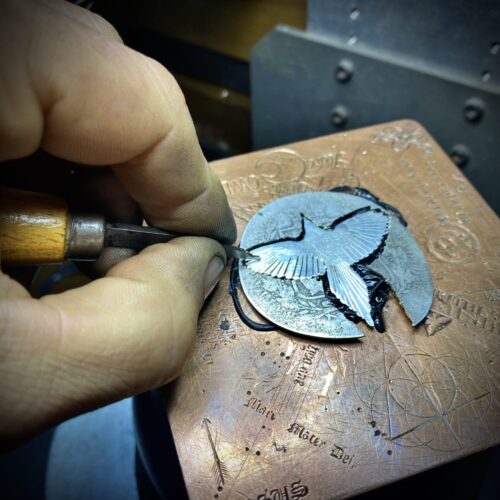 A handmade and and carved silver magpie in the making