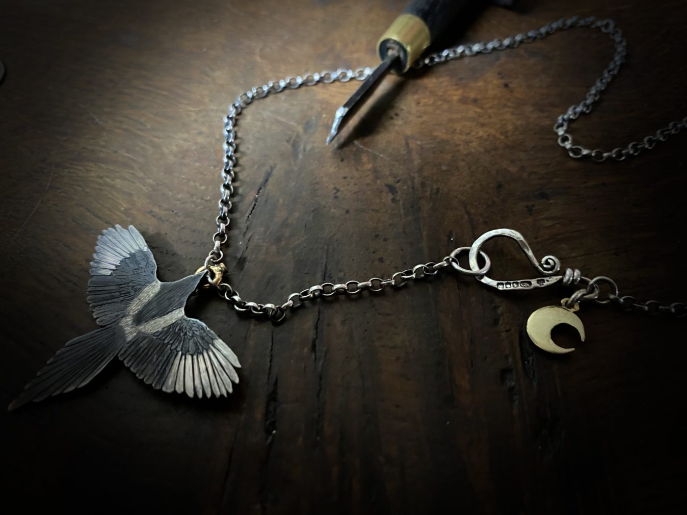 handmade silver Magpie necklace flying off with 18ct gold and emerald treasure in beak. Made in England with love and passion for treasure. Each piece is completely unique and original made in artisan studio in Cambridge and Newcastle