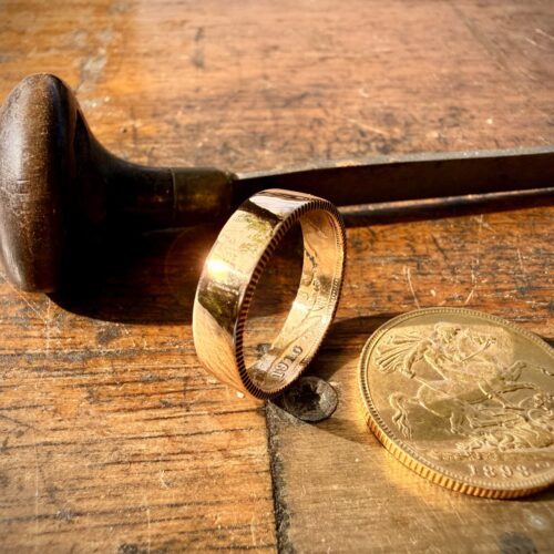 Gold ring and coin on wood